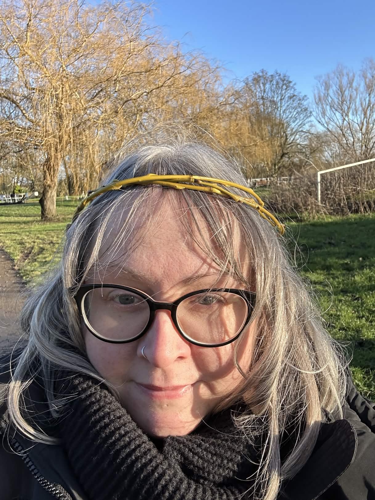 Becky is standing in a park and wearing all her winter layers